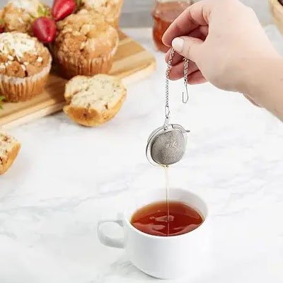 Boule pour le thé Inox Premium au dessus d'une tasse blanche