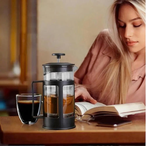Cafetiere poussoir RapidCafé sur une table avec café et jeune femme qui lit un livre