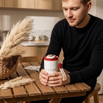 Mug isotherme Thermoperfect dans les mains d'un homme assis à table