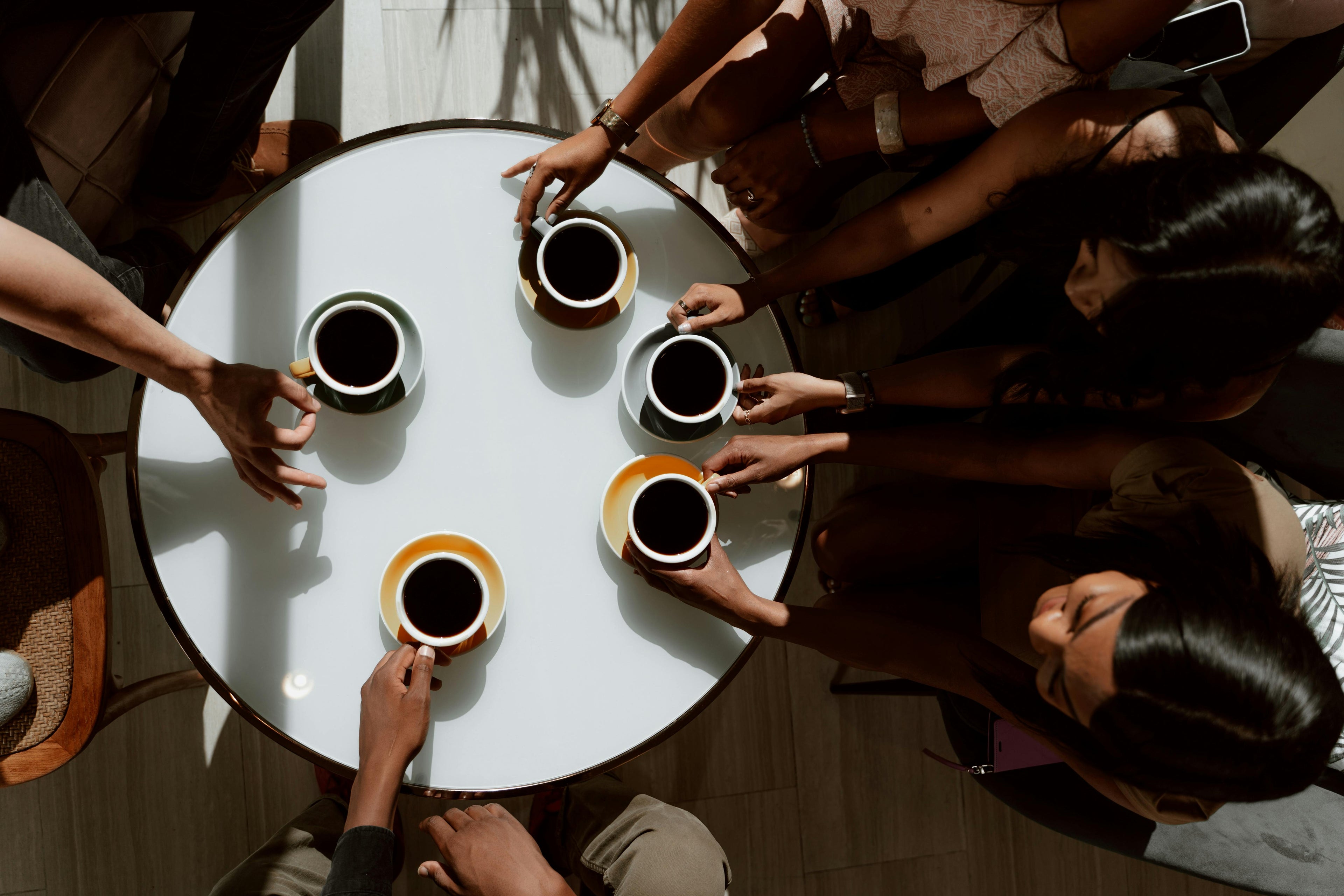 personnes autout d'une table dégustant du café