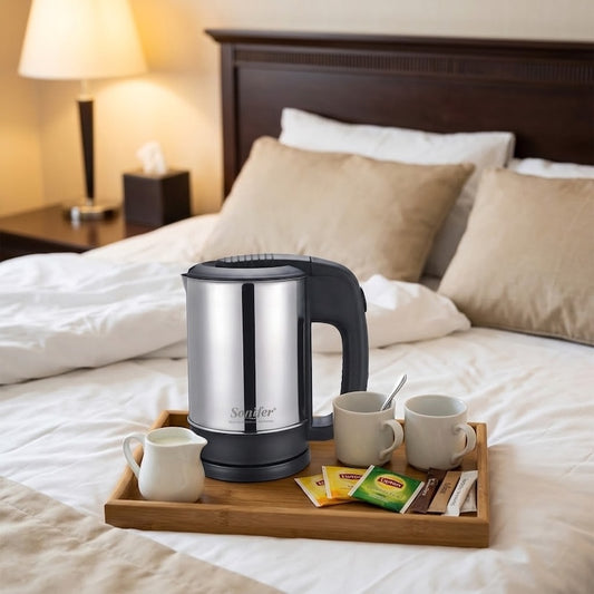 Petite bouilloire Voyage Compact sur un plateau posé sur un lit