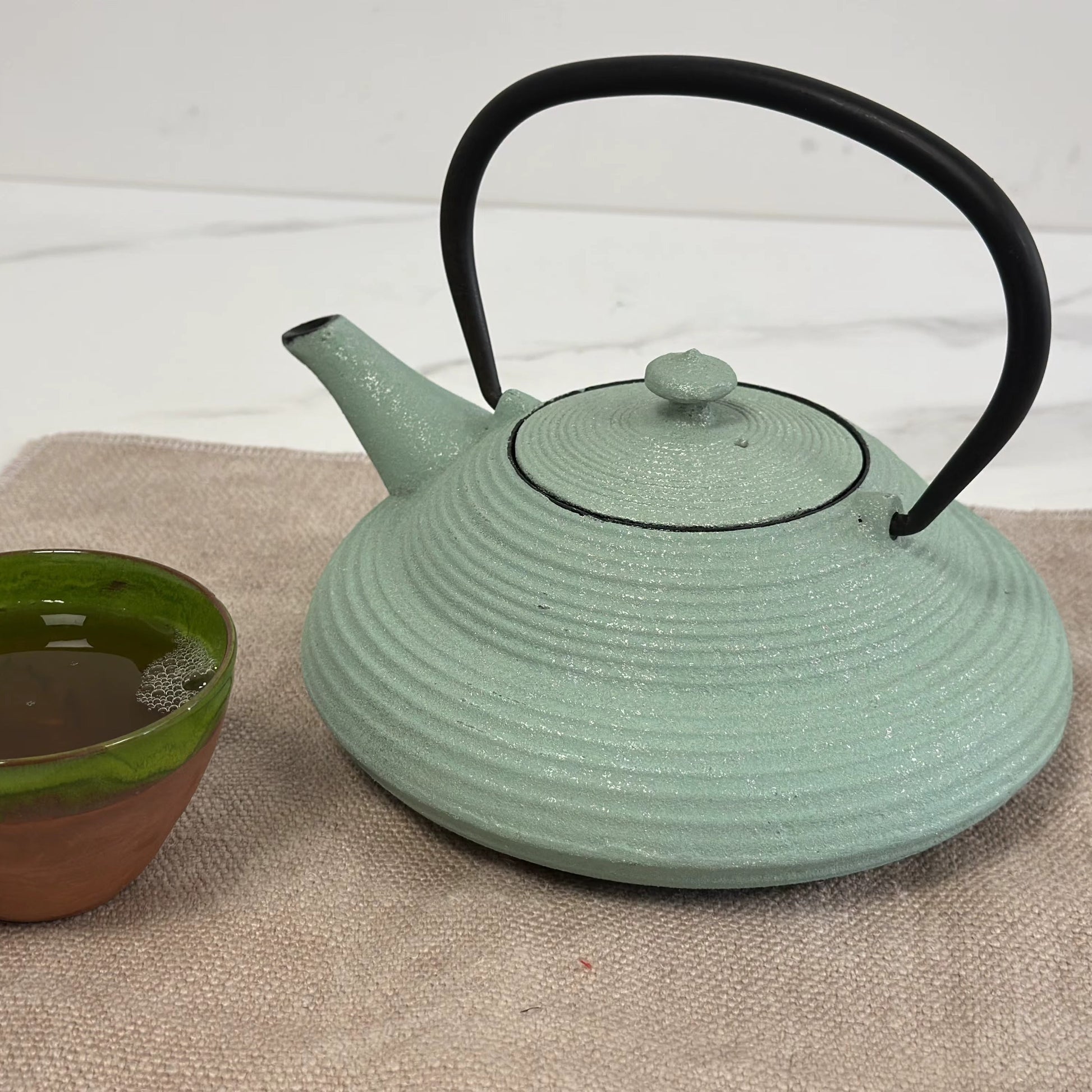 Theiere en fonte Japonaise 750ml  sur napperon avec tasse de thé